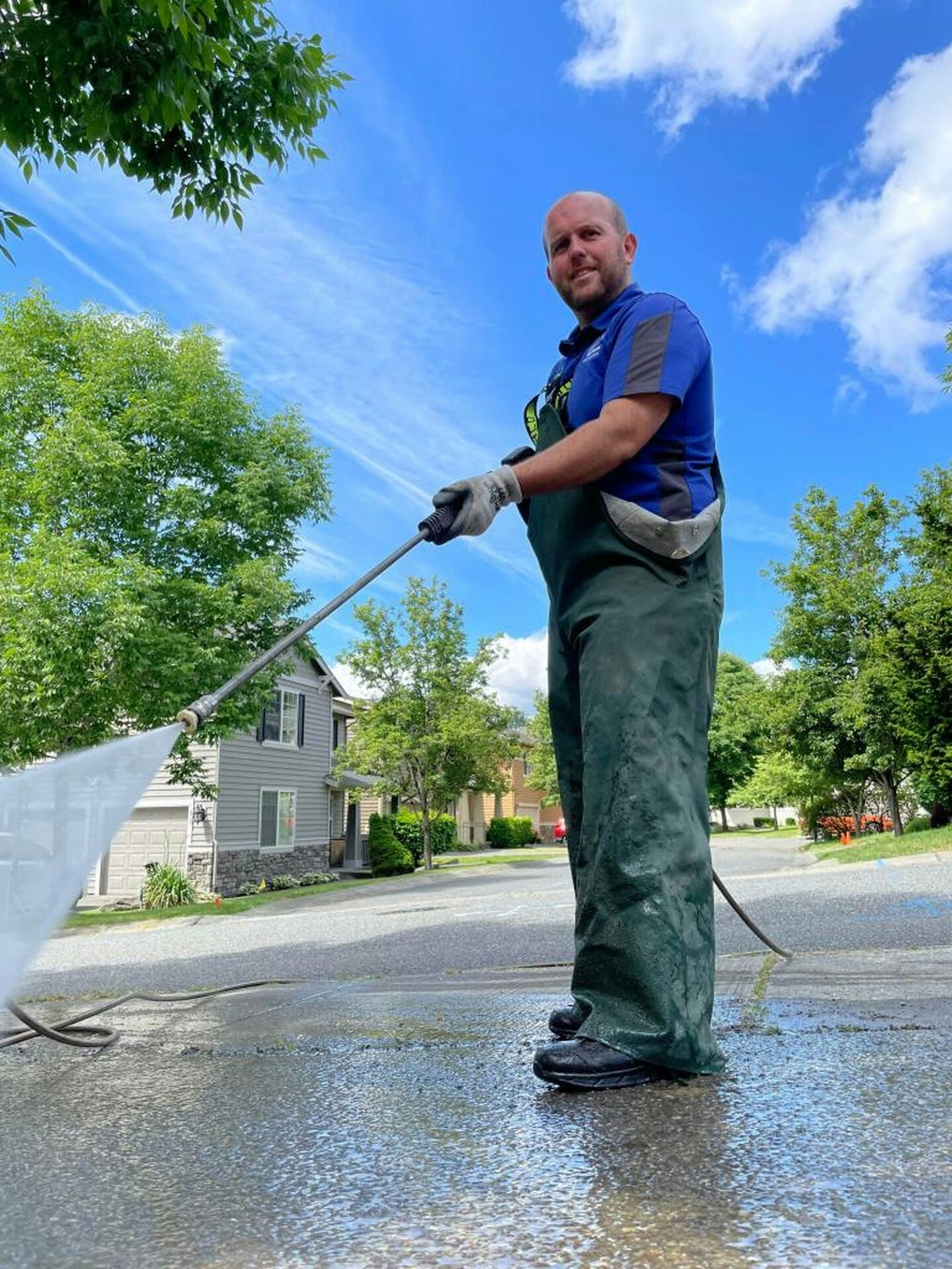 Worker water-blasting a concrete driveway surface